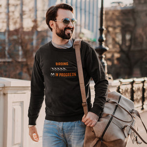 Black birding sweatshirt with the words Birding in Progress on the front around a loading progress bar. Worn by a man carrying a bag.