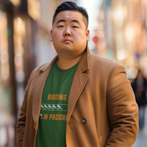 Forest green birding sweatshirt with the words Birding in Progress on the front around a loading progress bar. Worn by a man in a coat.