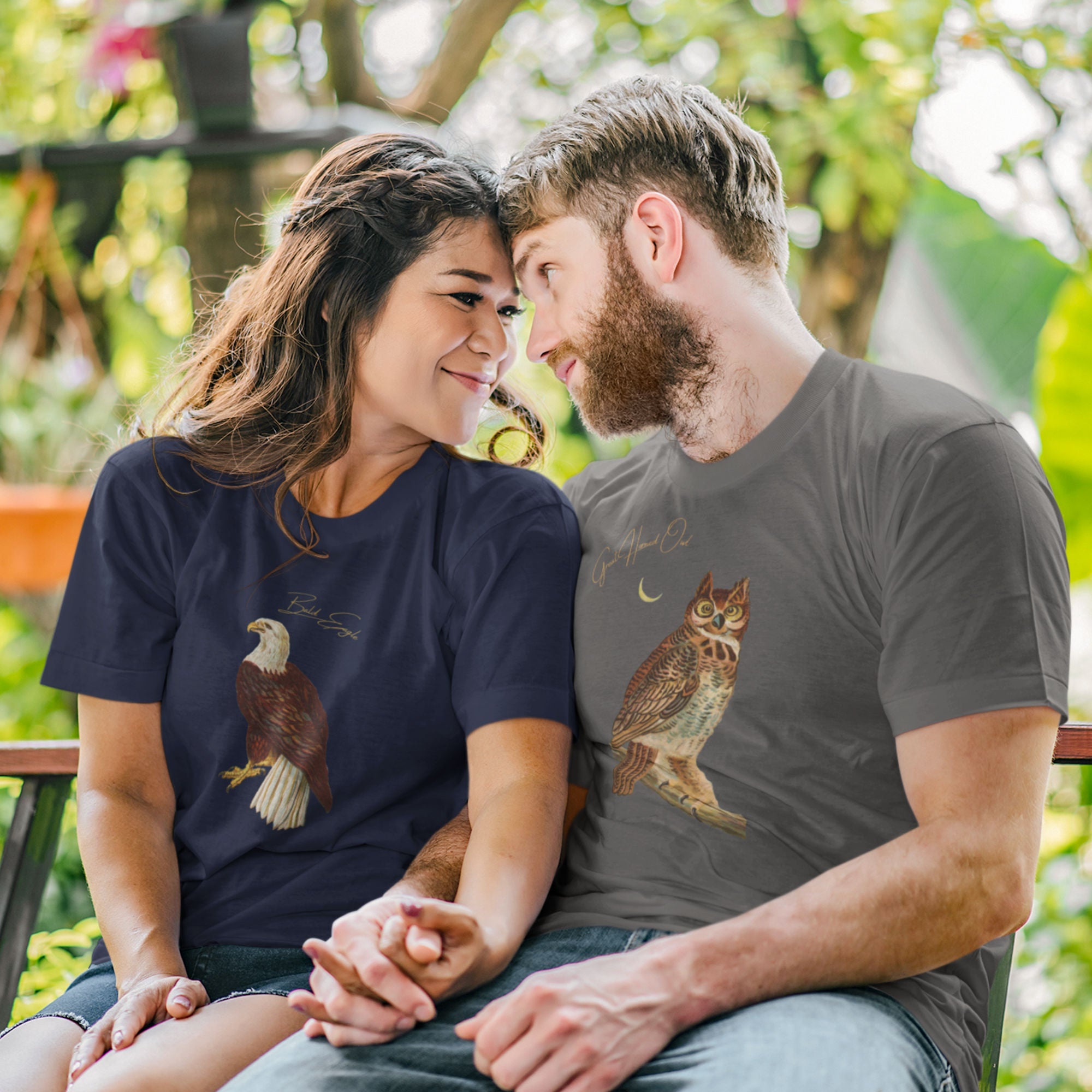 Asphalt gray bird shirt with vintage owl art and the words "Great Horned Owl" on the top right. Worn by a man on a park bench with his girl.