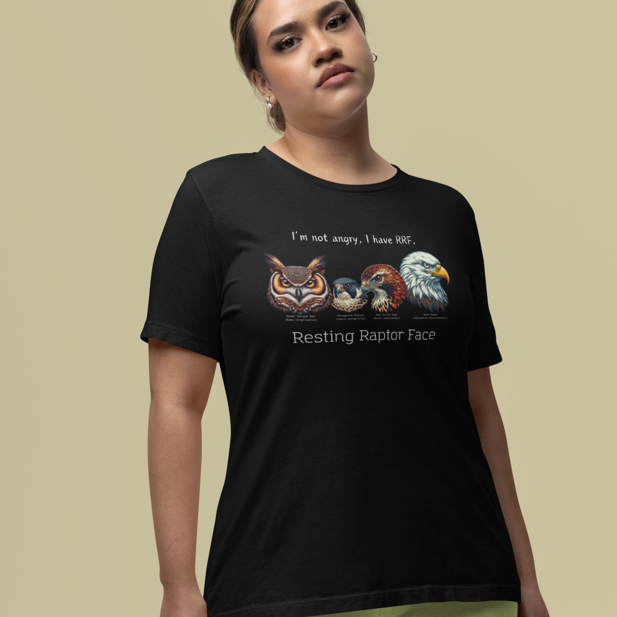 A black bird shirt with a great horned owl, a peregrine falcon, a red-tailed hawk and a bald eagle. The shirt has text that says, I'm not angry, I have RRF. Resting Raptor Face. Worn by a woman.