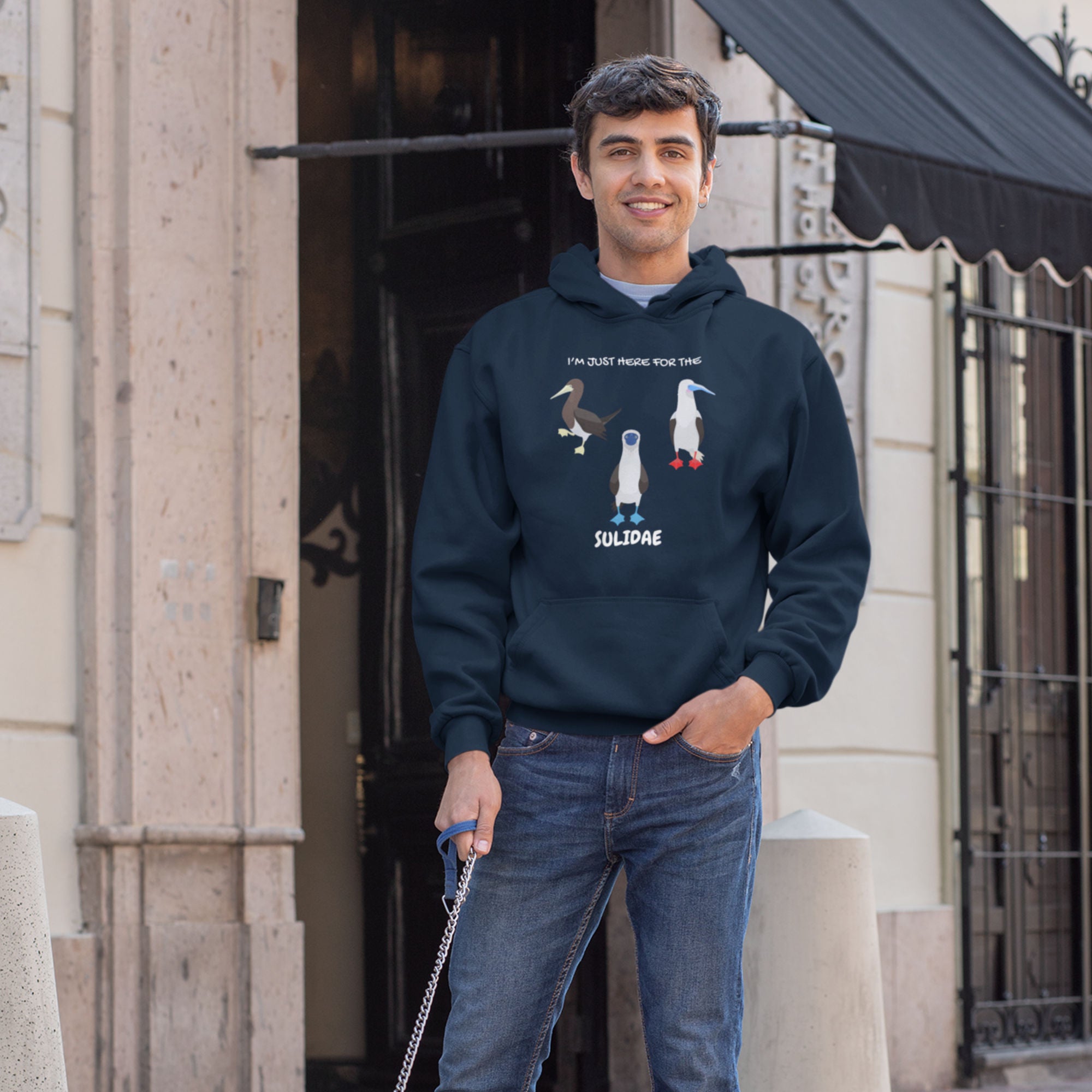 Navy birder hoodie with a red-footed, blue-footed and brown booby on it, but referencing only the scientific family name for the bird. Worn by a man.