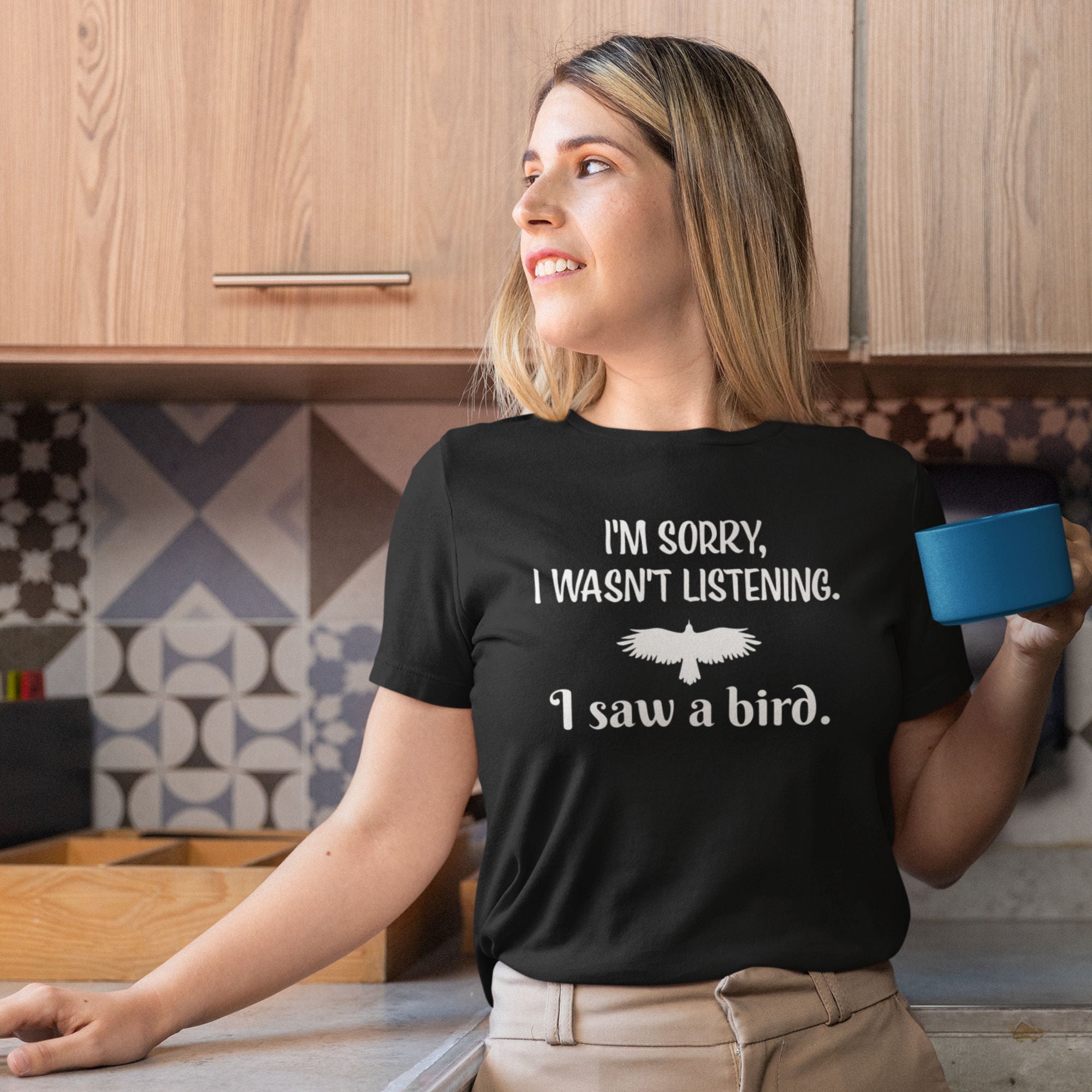 Navy blue women's bird t-shirt with the words I'm sorry I wasn't listening, I saw a bird. And a graphic of a bird flying.