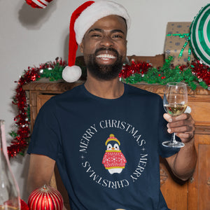 Navy blue unisex bird t-shirt with Merry Christmas on the front in a circle that surrounds a cute penguin in a hat and a sweater. Worn by a man enjoying some wine.