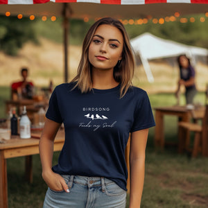 Navy t-shirt with the words Birdsong feeds my soul placed above and below a white graphic of 4 birds on a branch. Worn by a woman.