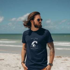 Navy blue unisex t-shirt with a quill and an ink pot and the words, "Feather for your Thoughts." Worn by a man on the beach.