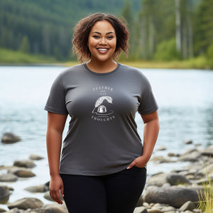 Grey unisex t-shirt with a quill and an ink pot and the words, "Feather for your Thoughts." Worn by a woman by a river.