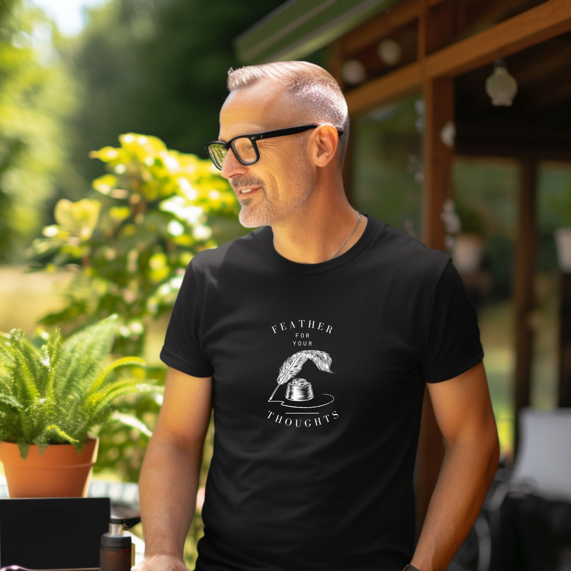 Black unisex t-shirt with a quill and an ink pot and the words, "Feather for your Thoughts." Worn by a man.