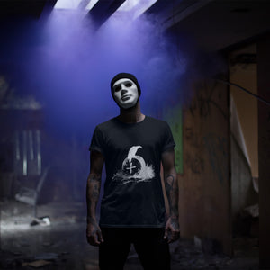 Black bird t-shirt with a picture of raven sitting on top of an unmarked grave. Worn by a man with a mask on in an abandoned building.