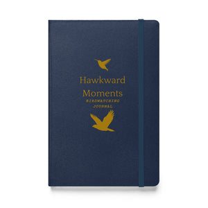 Hardcover bound birding notebook in navy blue with the words, "Hawkward Moments, Birdwatching Journal" on the front with silhouettes of birds above and below.