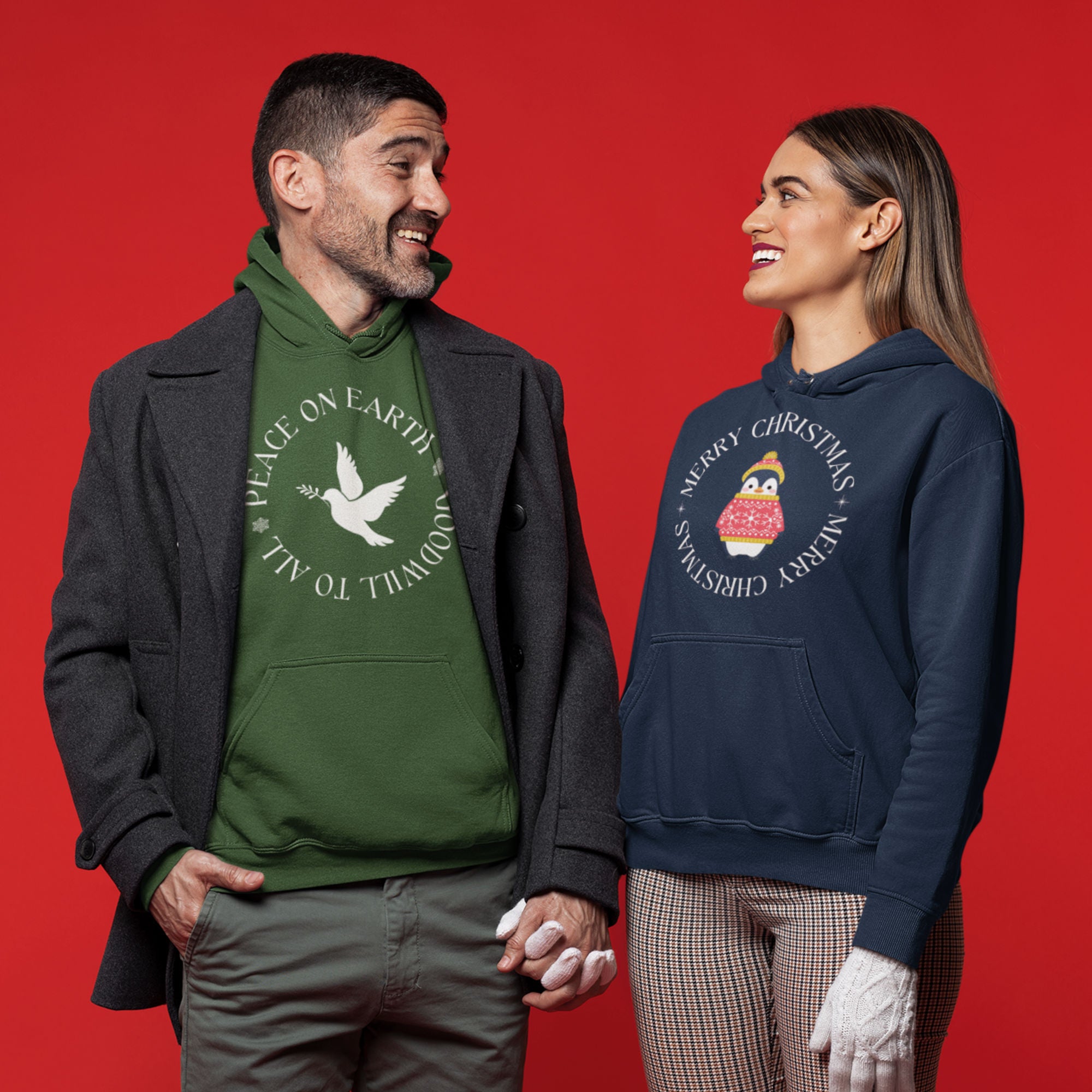 Forest green unisex hoodie that says Peace on Earth Goodwill to All in a circle surrounding a dove of peace. Worn by a man in a coat holding hands with a woman in a christmas themed hoodie.