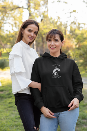 Black unisex hoodie with a quill and an ink pot and the words, "Feather for your Thoughts." Worn by a woman standing next to her daughter.