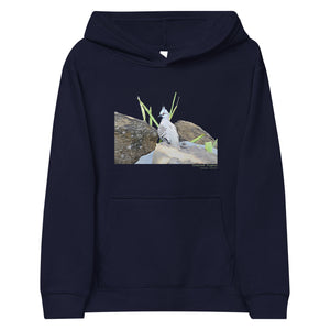 Navy unisex youth bird hoodie with a graphic of a crested pigeon among some rocks and grass on front, and the words crested pigeon written below and the scientific name below that.