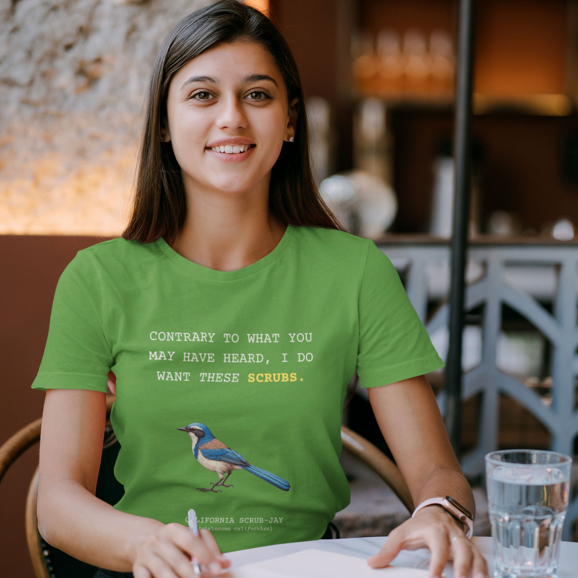 A leaf green unisex bird shirt with the words I want these scrubs on the front above an illustration of a California scrub-jay.