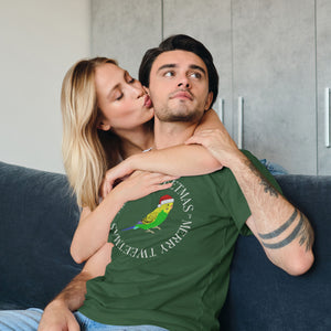 Forest green unisex bird t-shirt with a budgie in a santa hat surrounded by the words Merry Tweetmas, separated by to seed sprigs. Worn by a man getting a kiss on the cheek from a lady.