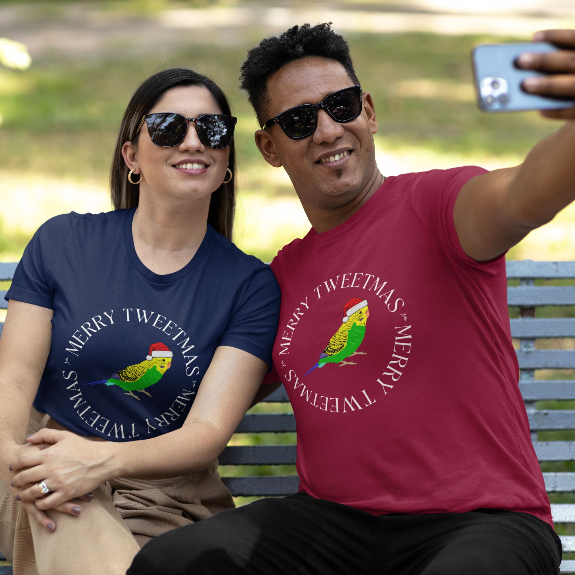 Red unisex bird t-shirt with a budgie in a santa hat surrounded by the words Merry Tweetmas, separated by to seed sprigs.