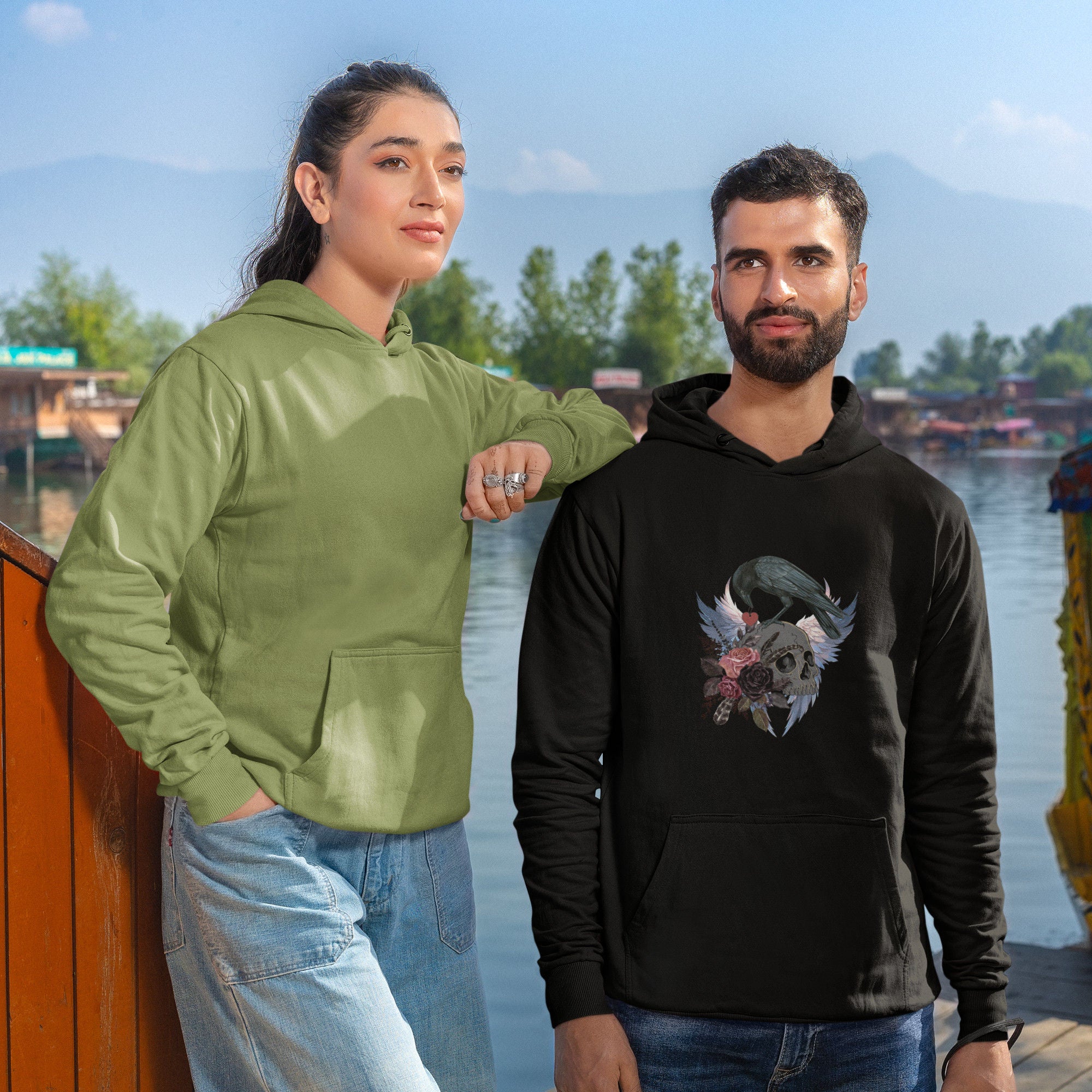 White unisex bird hoodie with a crow holding a heart pendant, perched upon a skull, surrounded by wings and flowers.