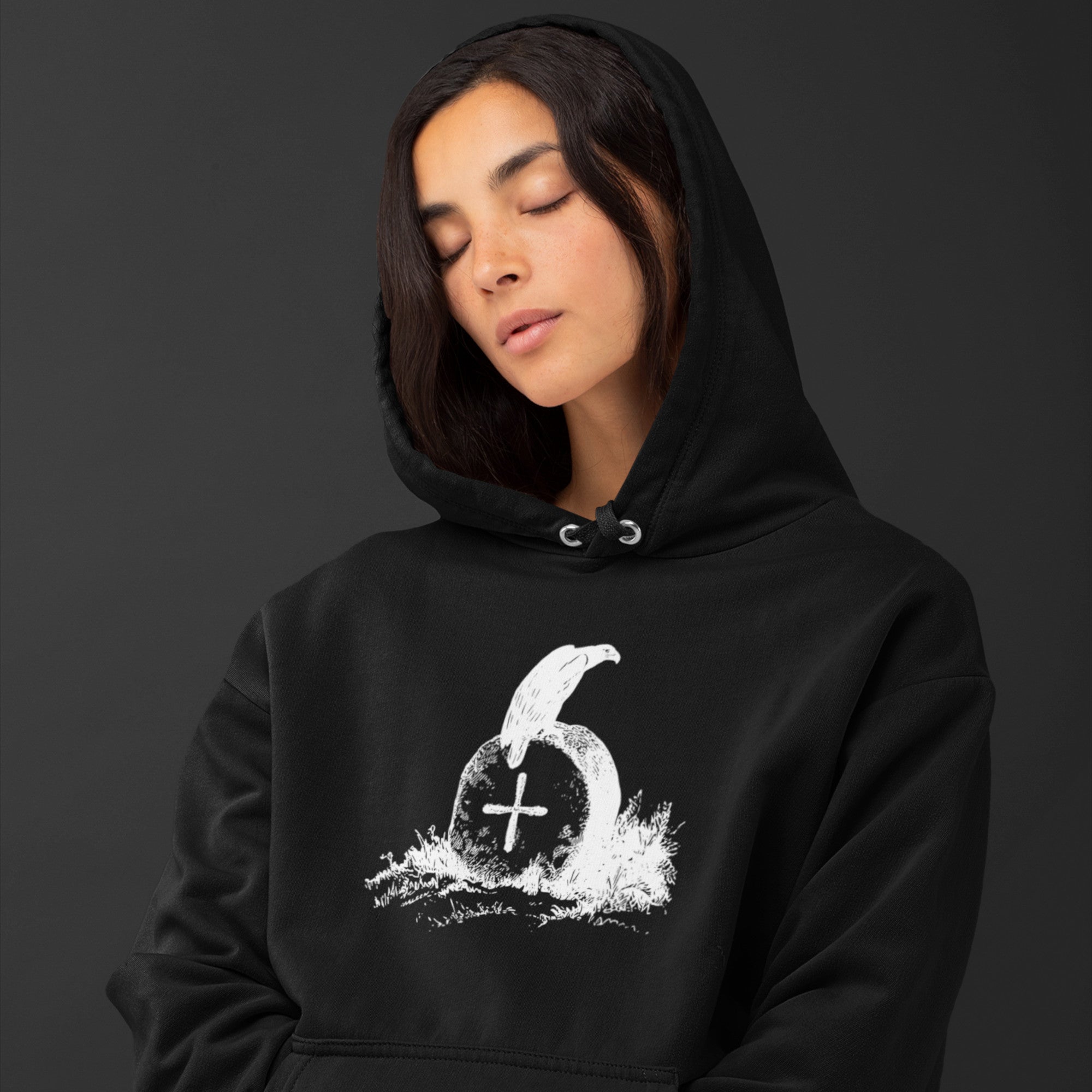 Black unisex bird hoodie with a picture of raven sitting on top of an unmarked grave. Worn by a woman.