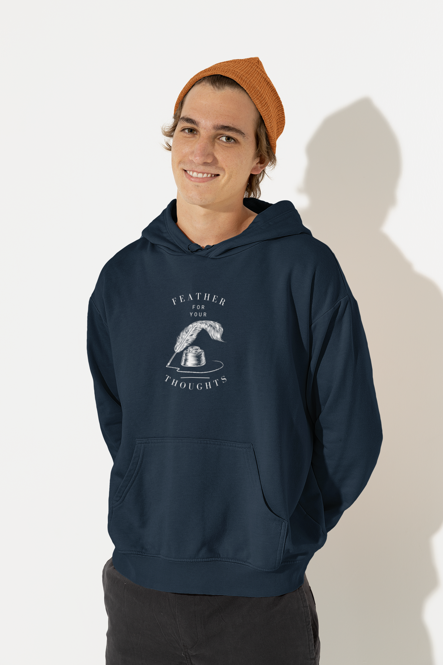 Navy blue unisex hoodie with a quill and an ink pot and the words, "Feather for your Thoughts." Worn by a man in a beanie.