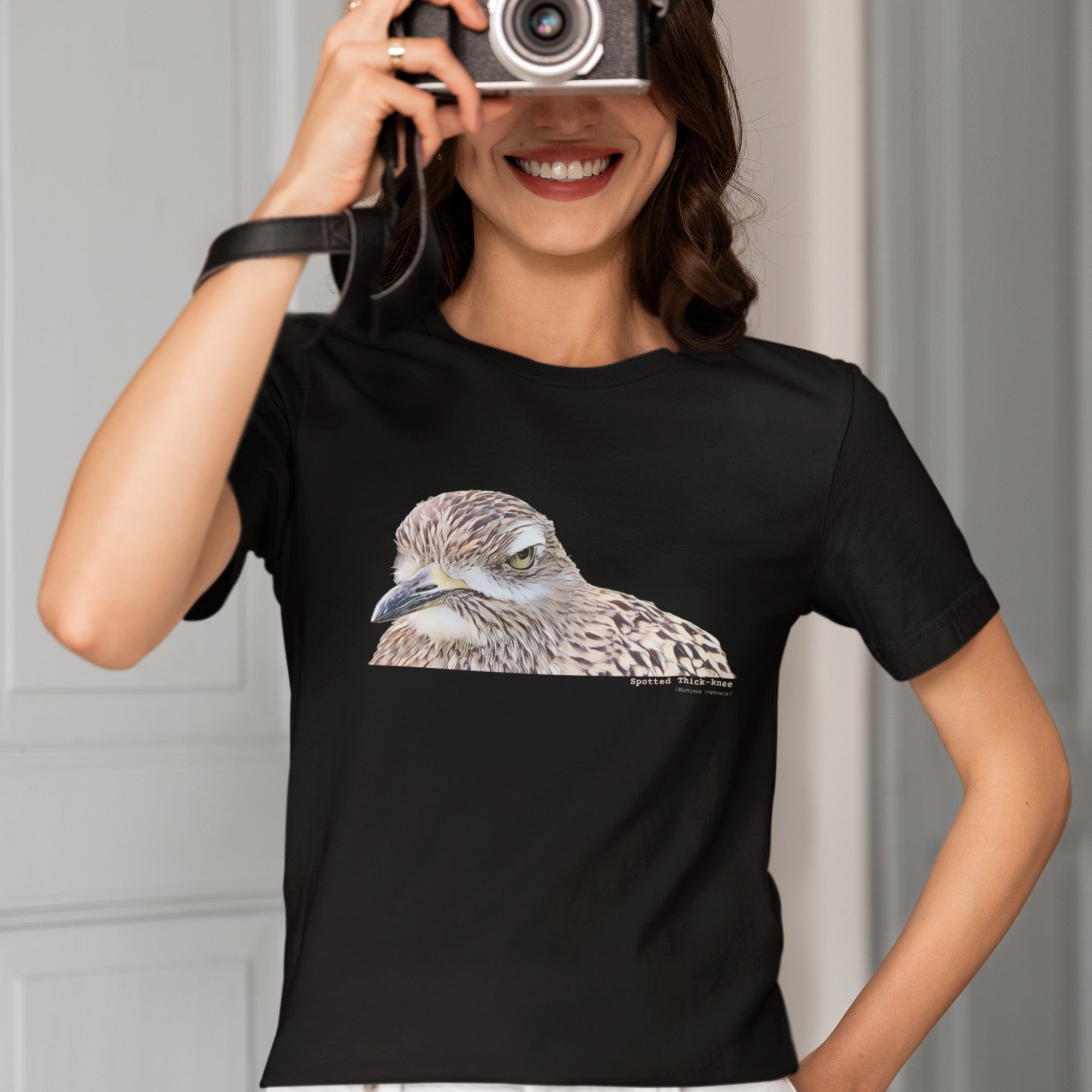 Black unisex bird shirt with a lifelike illustration of a Spotted Thickknee on the front and the words Spotted Thickknee in small print below, with the scientific name included.