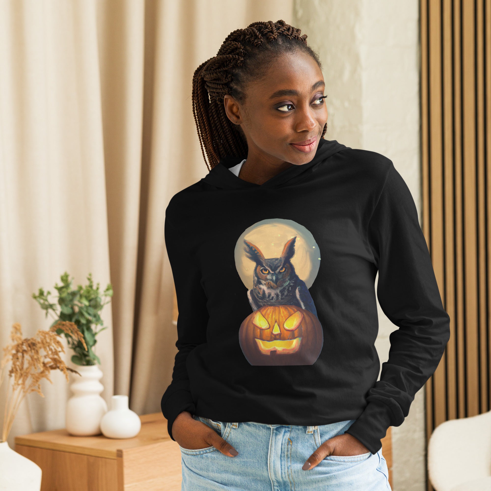 Black, long-sleeve, hooded bird t-shirt with a great horned owl sitting behind a pumpkin, outlined by the full moon. Worn by a woman.