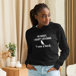 Black long-sleeved hooded bird shirt with the words I'm sorry I wasn't listening, I saw a bird. And a graphic of a songbird. Worn by a woman.