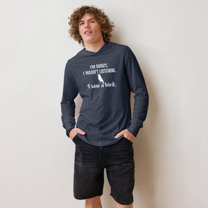 Heather navy blue long-sleeved hooded bird shirt with the words I'm sorry I wasn't listening, I saw a bird. And a graphic of a songbird. Worn by a man.