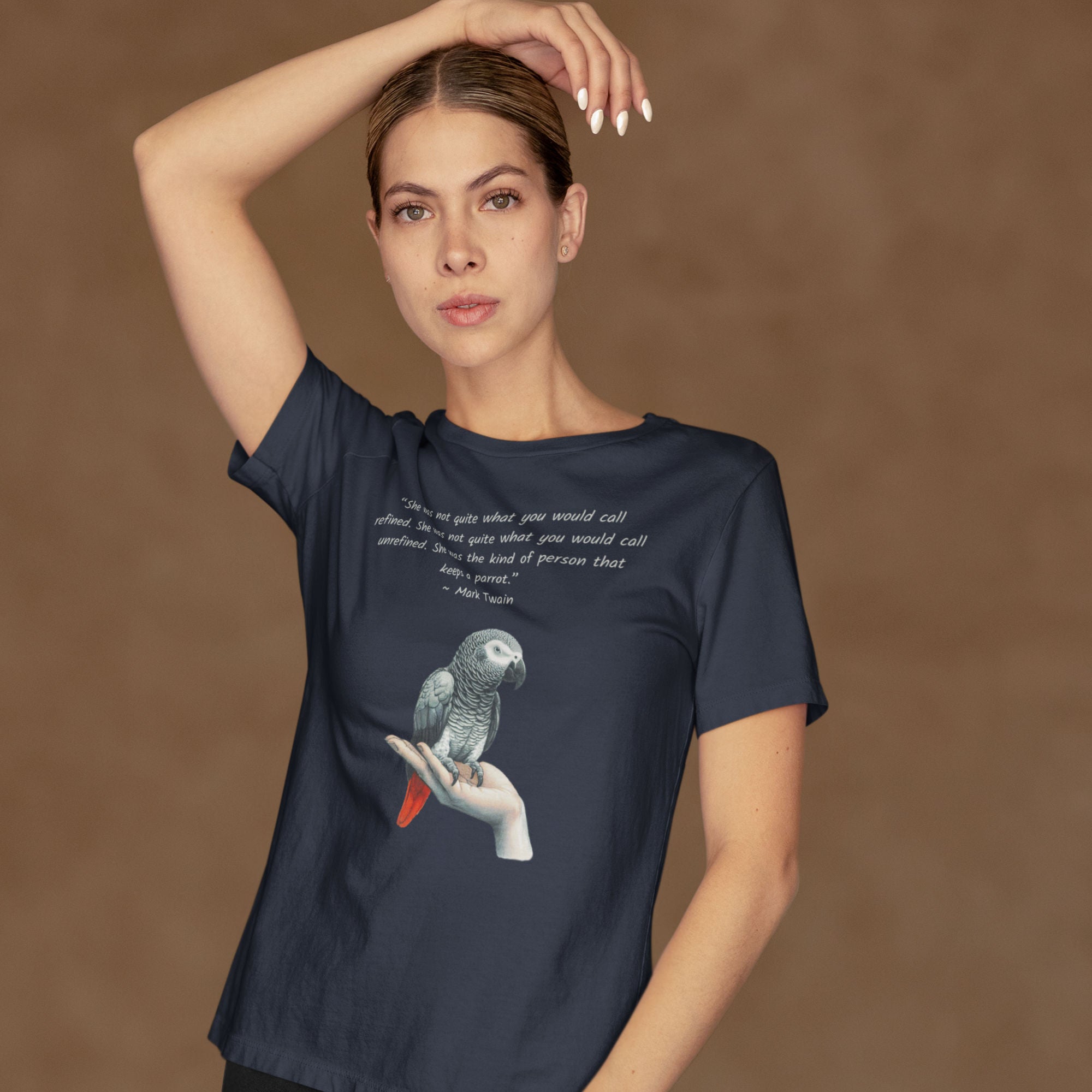 Navy bird shirt with a Mark Twain woman who keeps parrot quote and a illustration of an african grey parrot perched on a hand beneath. Worn by a woman.