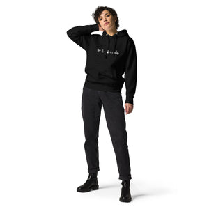 Unisex black birding hoodie celebrating bird watching and motorcycling with a graphic of binoculars, a bird, and a motorcycle. Worn by a woman.