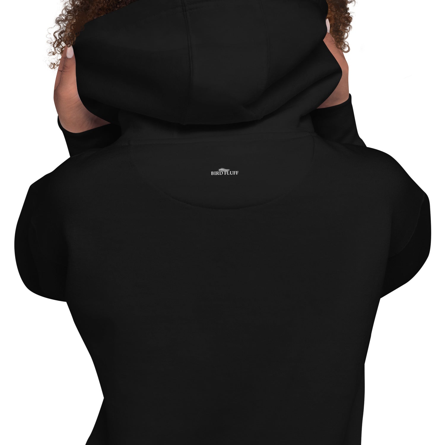 Black unisex hoodie with a picture of a great horned owl sitting on a carved pumpkin in front of a full moon on the front. Back of hoodie shown with model pulling up hood to reveal small brand logo near collar.