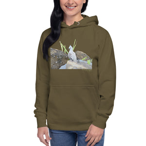 Army green premium hooded bird sweatshirt with a lifelike illustration of a crested pigeon among some rocks and grass. The name of the pigeon is below the picture, with the scientific name included. Worn by a woman.