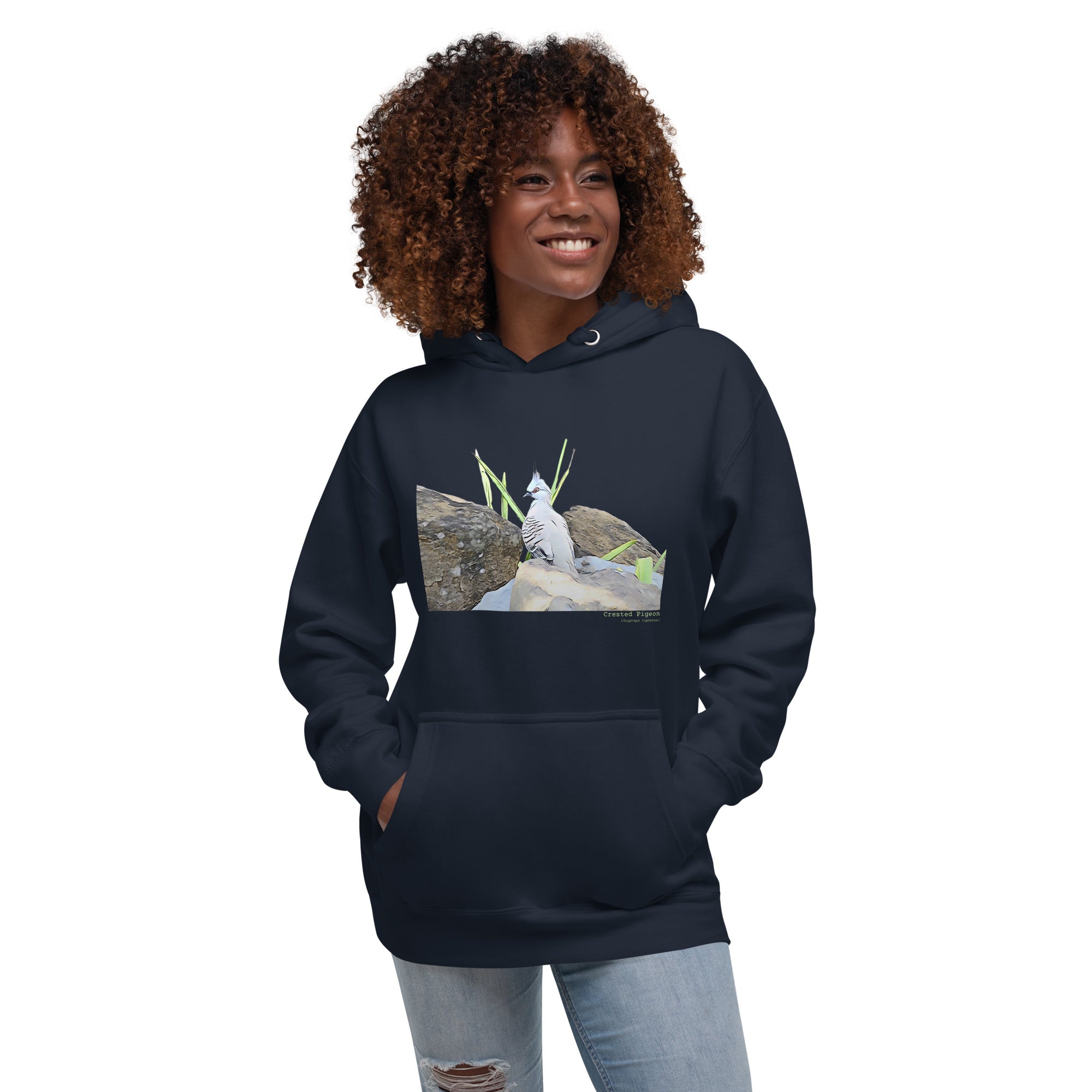 Navy premium hooded bird sweatshirt with a lifelike illustration of a crested pigeon among some rocks and grass. The name of the pigeon is below the picture, with the scientific name included. Worn by a woman.