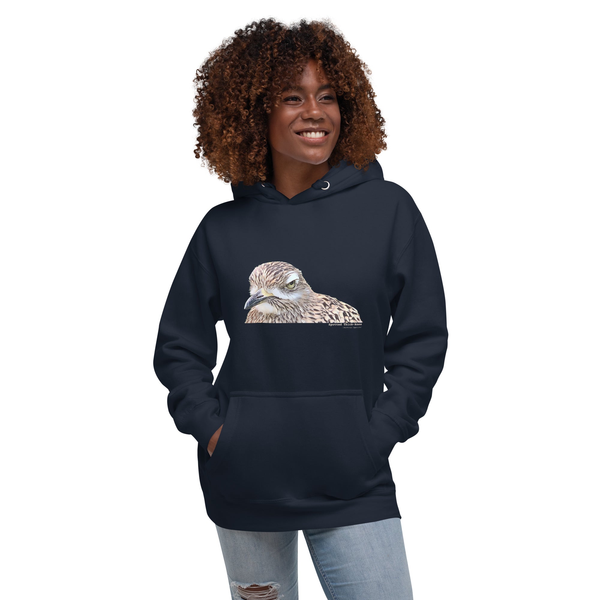 Navy unisex bird hoodie with an illustrated picture of a spotted thick-knee bird looking grumpy. The words spotted thick-knee are written below the illustration, including the scientific name. Worn by a woman.