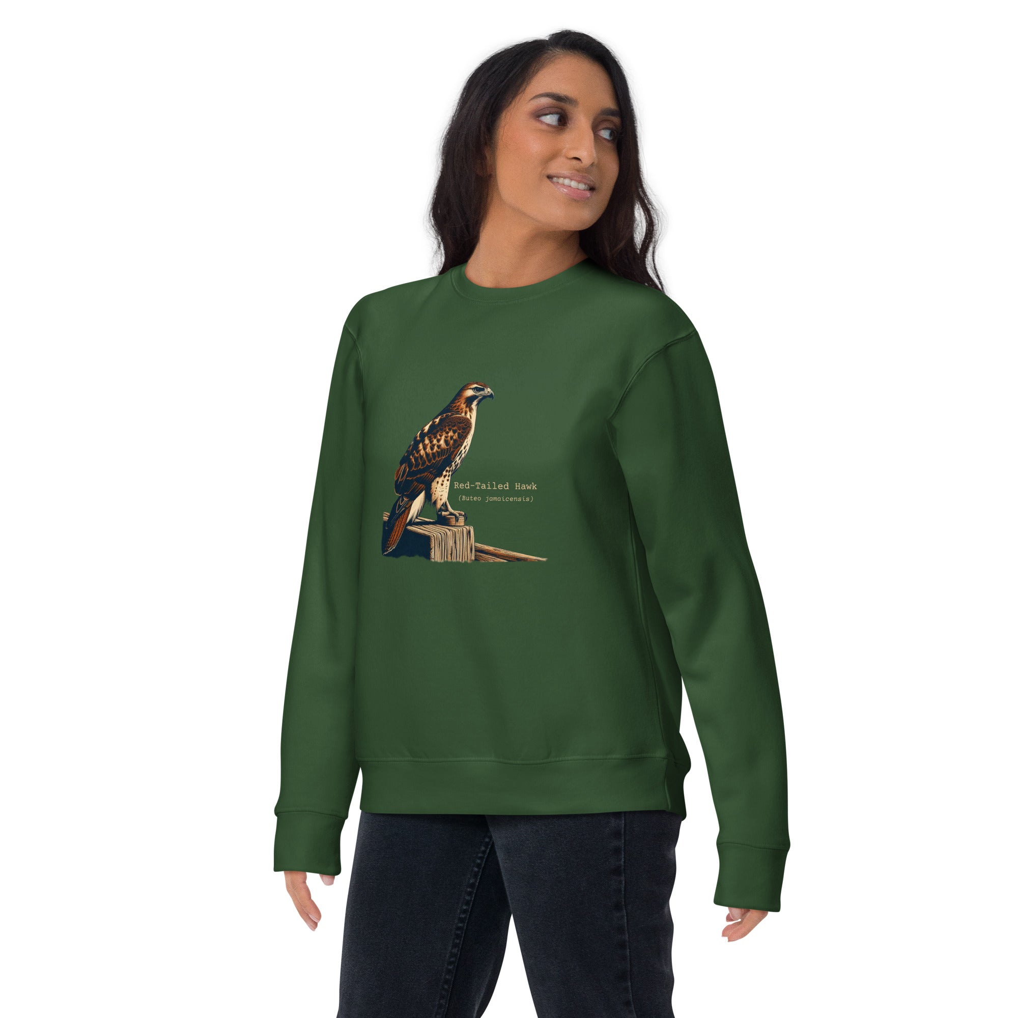 Green birding sweatshirt with an artistic depiction of a red-tailed hawk sitting on a fence and the common and scientific names for the bird next to it. Worn by a woman.