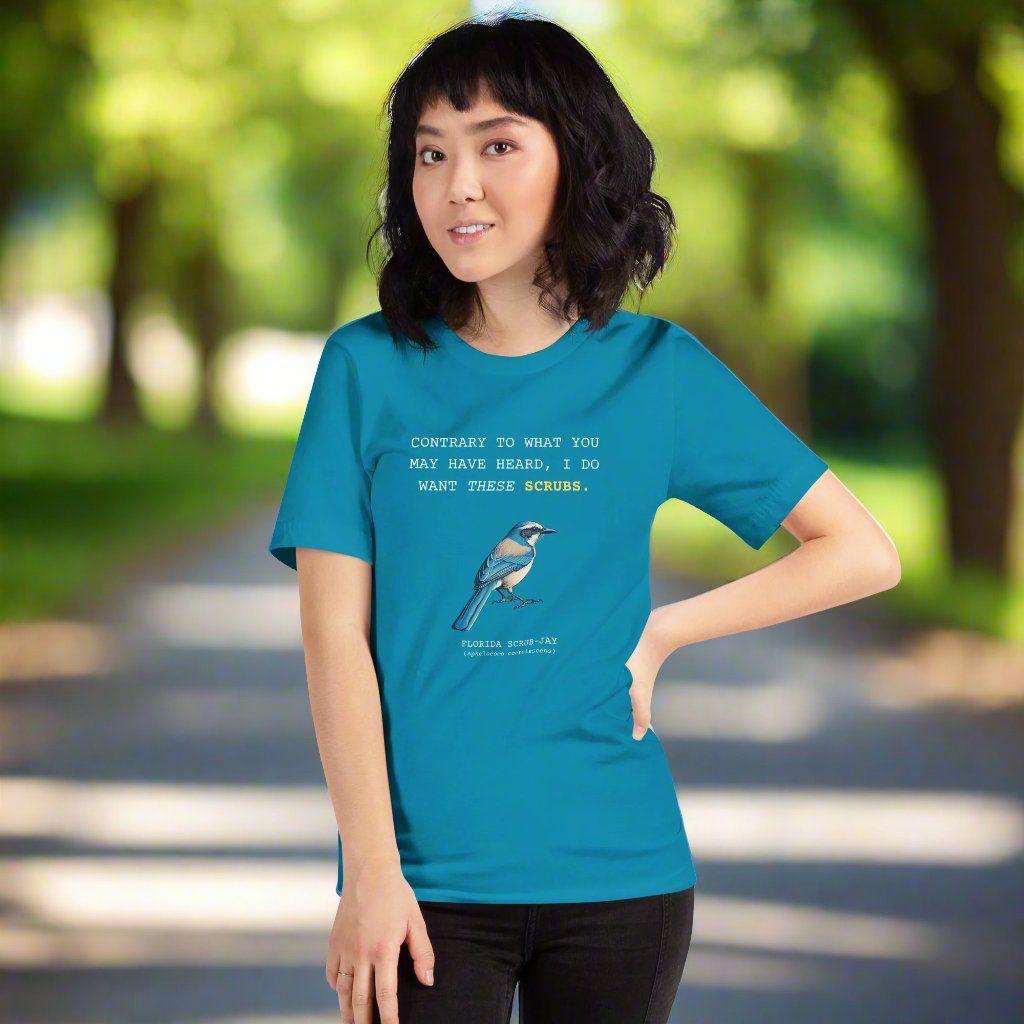 Aqua blue unisex bird shirt with the words I do want these scrubs on the front above an illustration of a Florida scrub-jay. Worn by a woman.