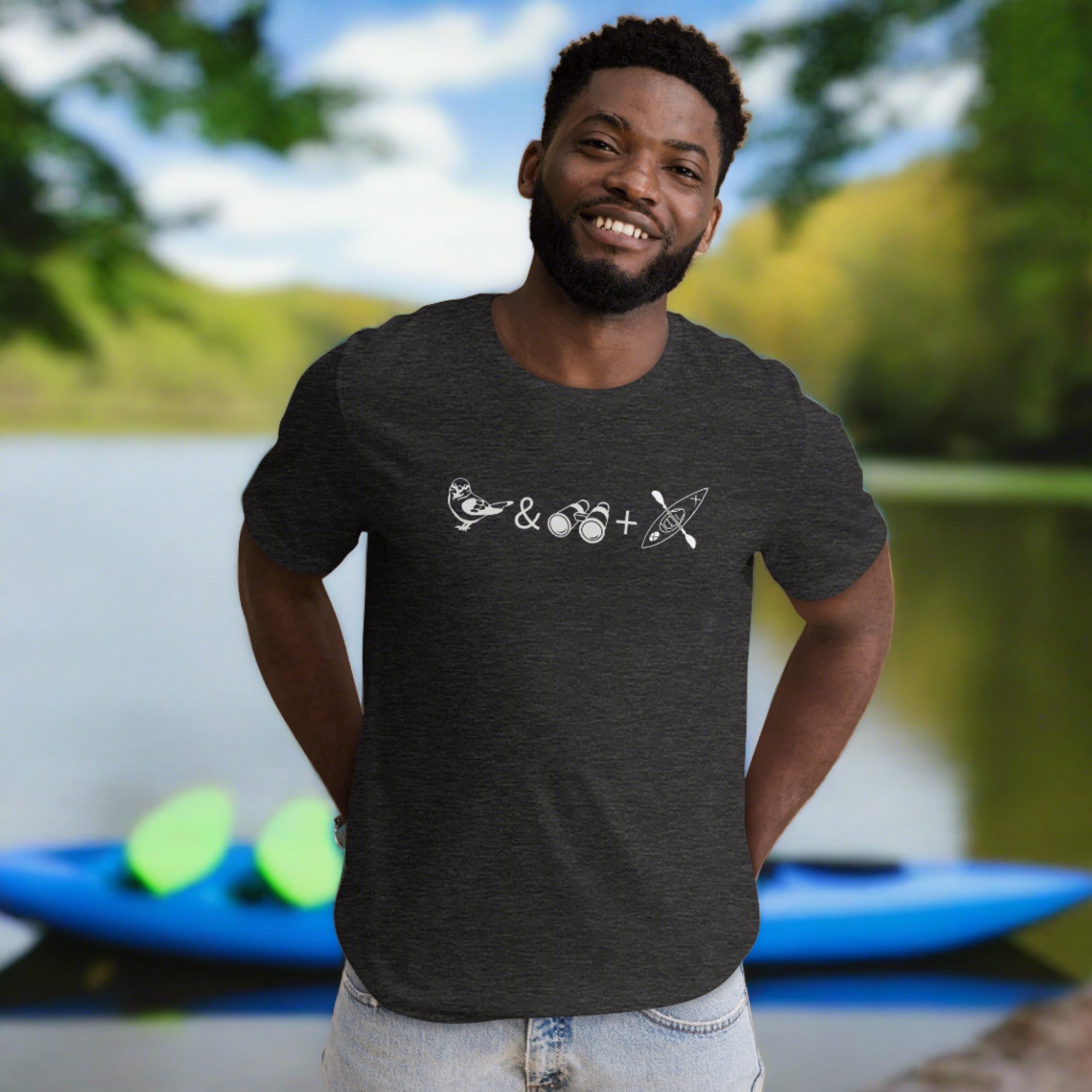 Unisex dark gray heather bird t-shirt celebrating bird watching and kayaking with a graphic of binoculars, a bird, and a kayak. Worn by a man.