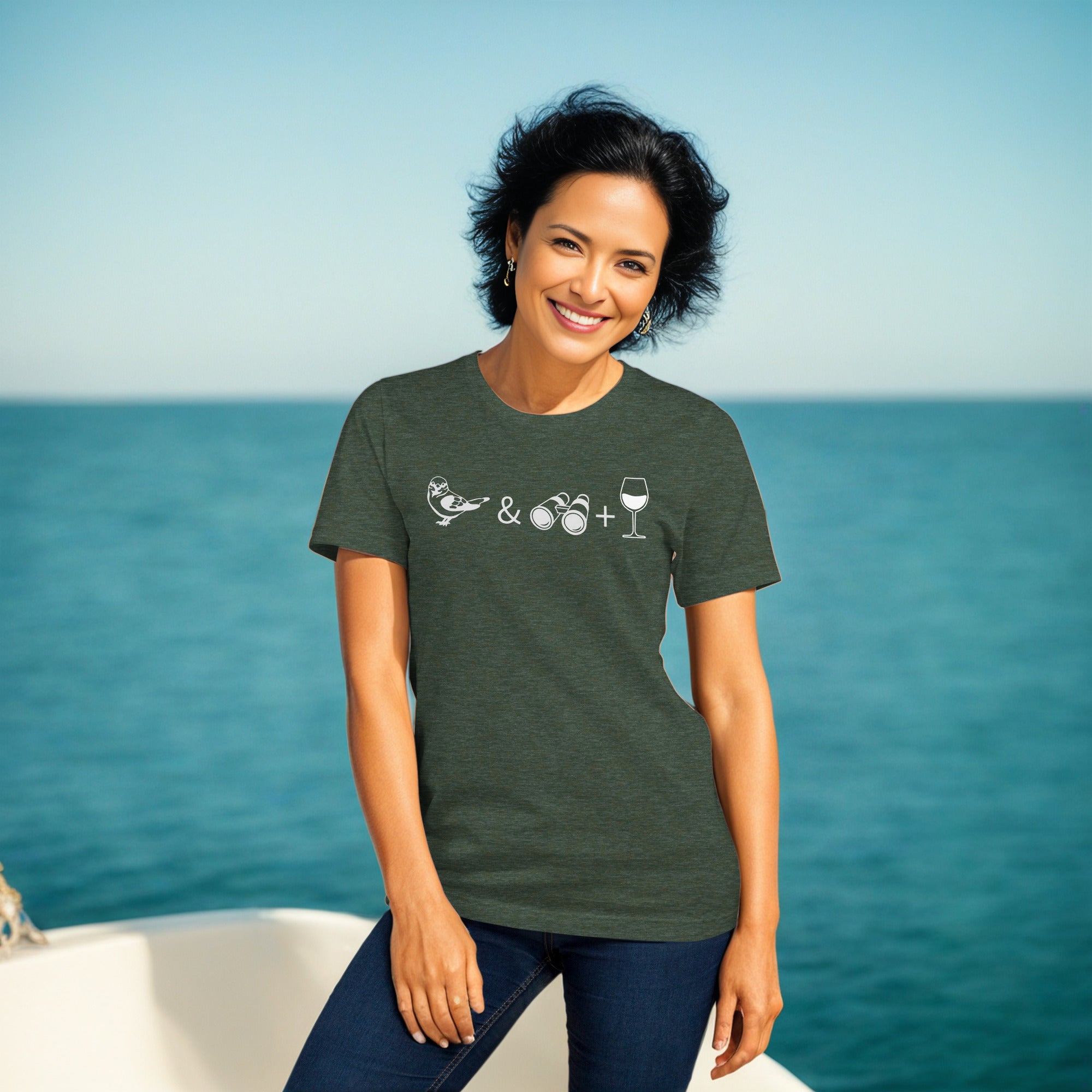 Unisex heather green bird t-shirt celebrating bird watching and wine drinking with a graphic of binoculars, a bird, and a glass of wine. Worn by a woman.