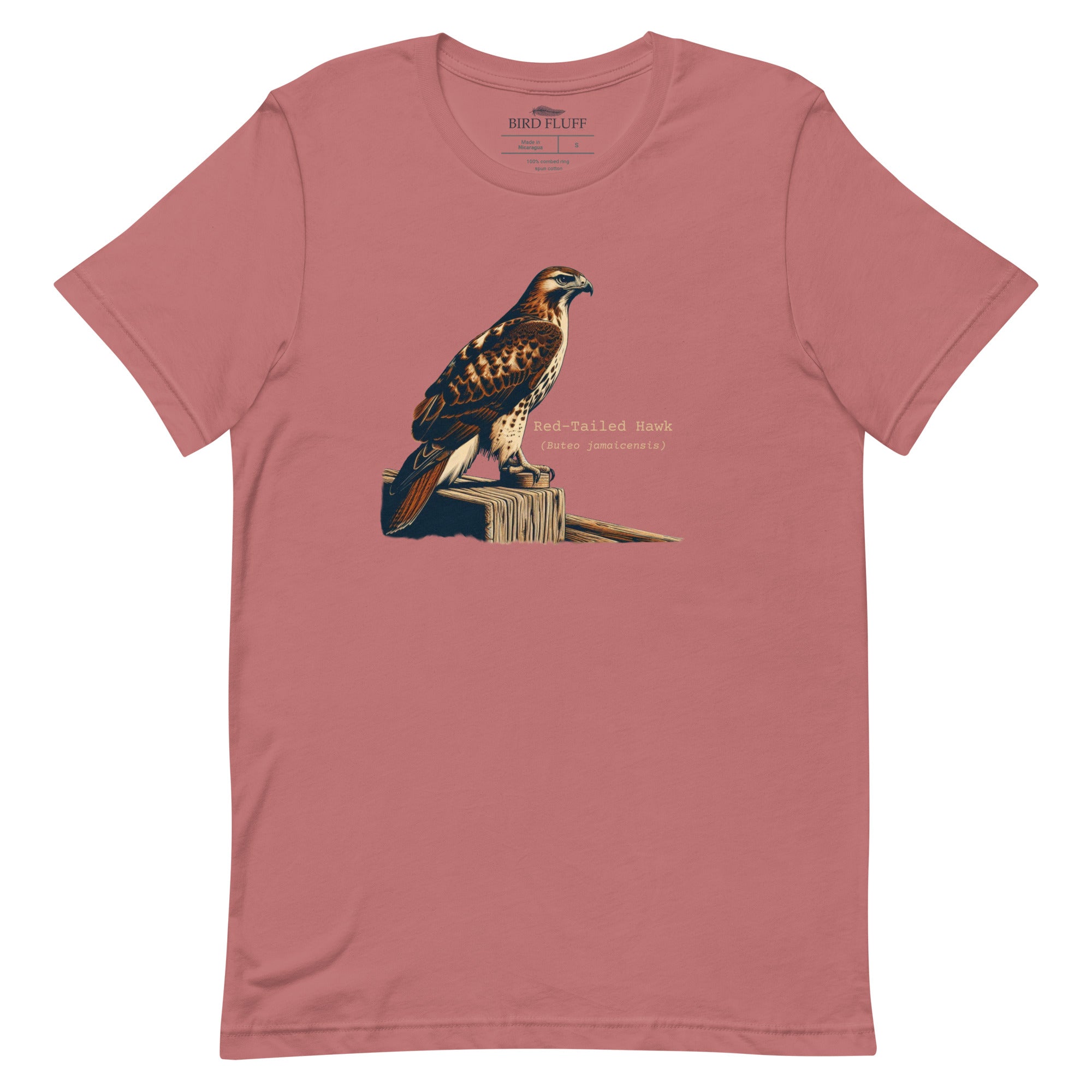 Mauve bird shirt with an artistic depiction of a red-tailed hawk sitting on a fence and the common and scientific names for the bird next to it.