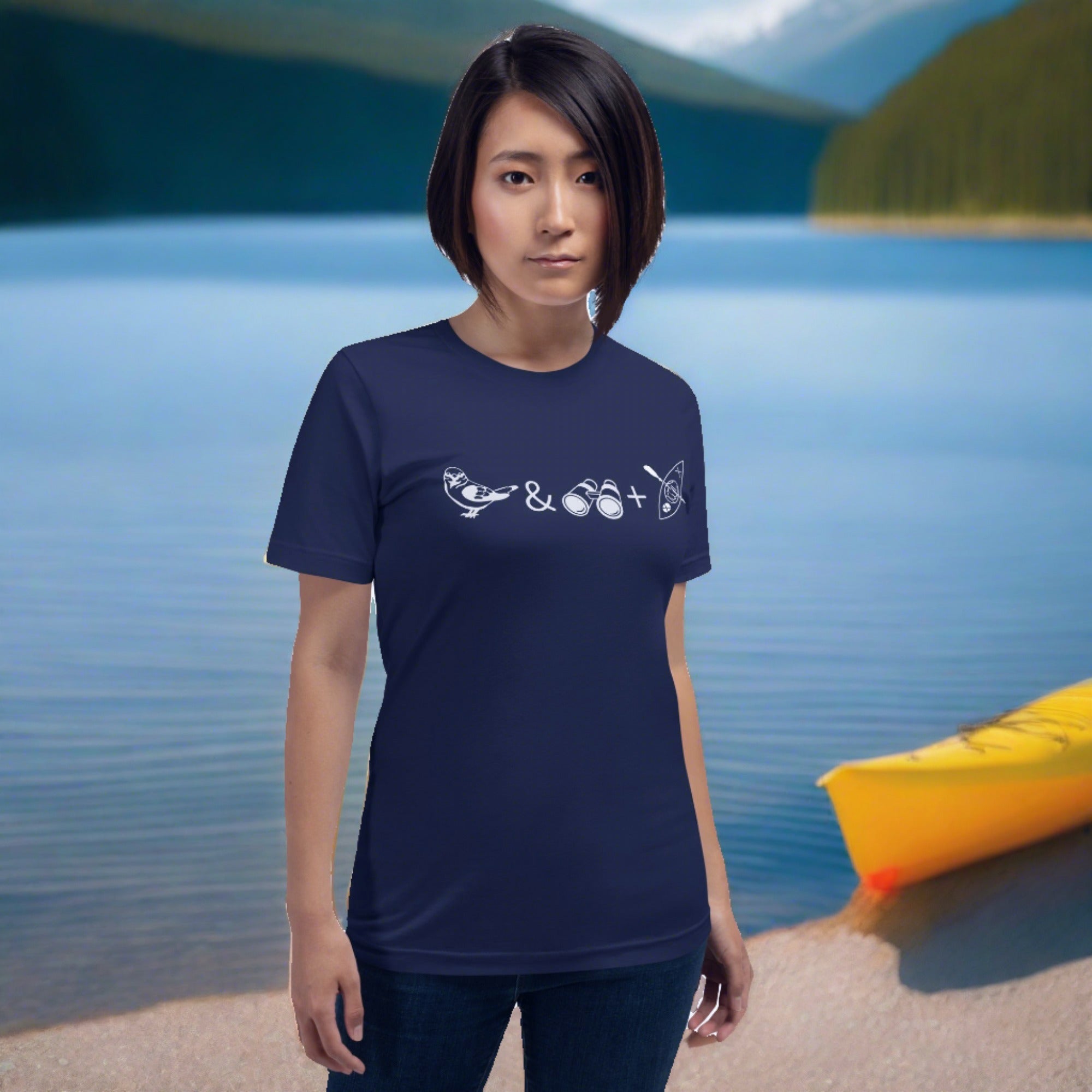 Unisex navy blue bird t-shirt celebrating bird watching and kayaking with a graphic of binoculars, a bird, and a kayak. Worn by a woman.