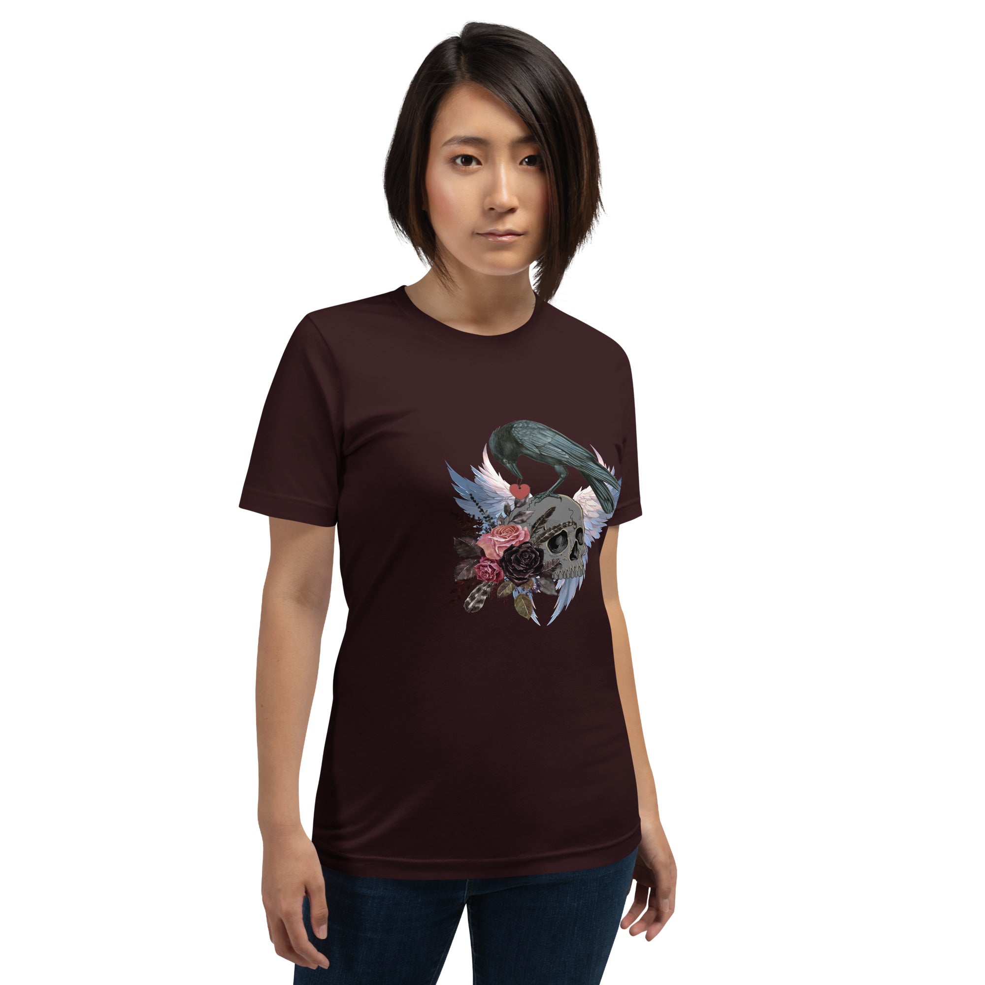 Gothic themed oxblood black bird shirt with a crow carrying a heart pendant, perched on a skull surrounded by flowers, feathers and wings. Worn by a woman.