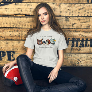 Woman sitting against a wall with a motorcycle helmet, wearing an off white bird shirt with a great horned owl, a peregrine falcon, a red-tailed hawk and a bald eagle. The shirt has text that says, I'm not angry, I have RRF. Resting Raptor Face.