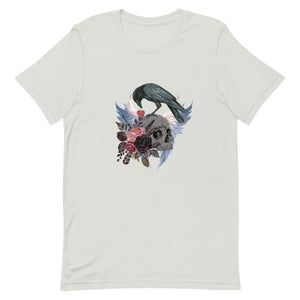 Gothic themed white bird shirt with a crow carrying a heart pendant, perched on a skull surrounded by flowers, feathers and wings.