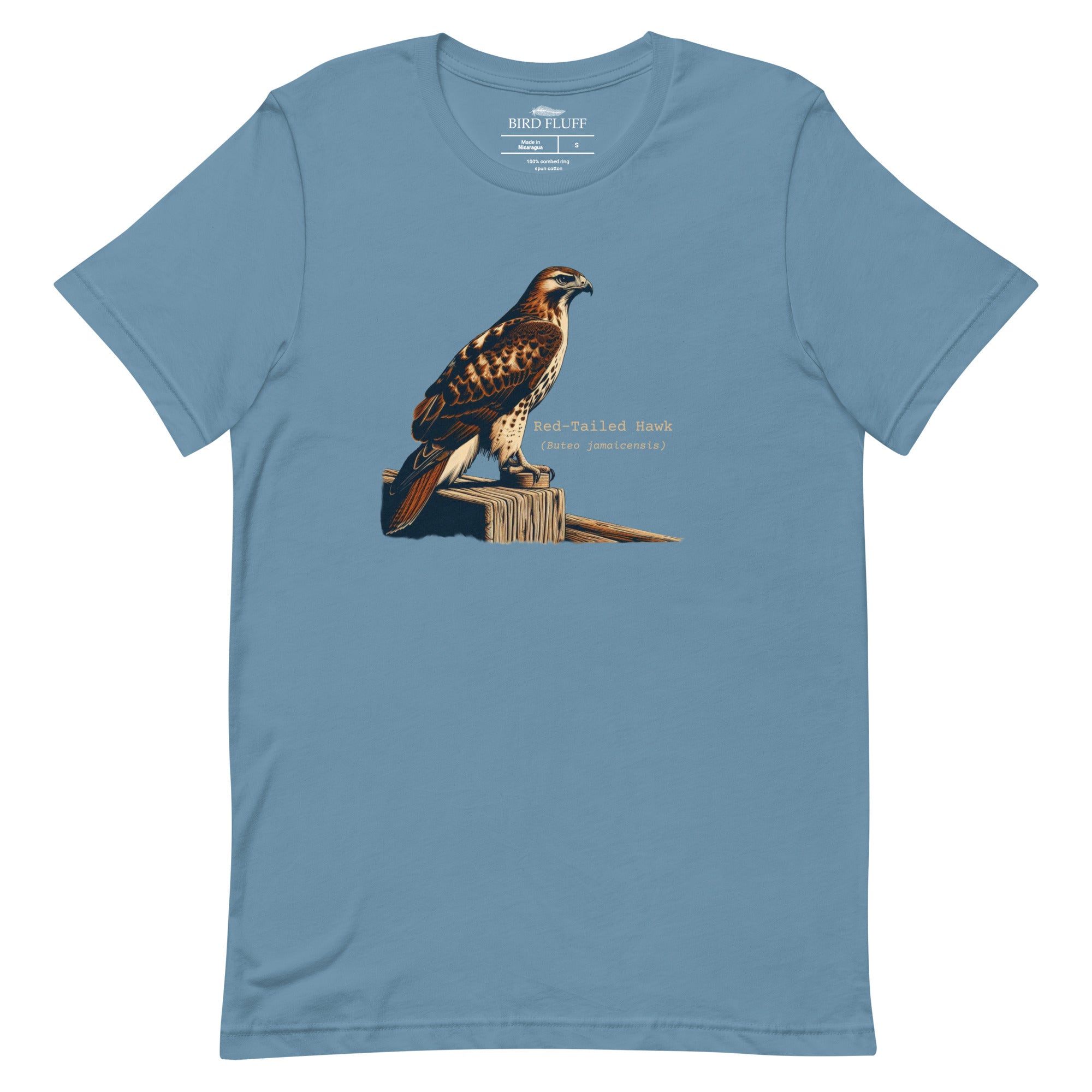 Steel blue bird shirt with an artistic depiction of a red-tailed hawk sitting on a fence and the common and scientific names for the bird next to it.