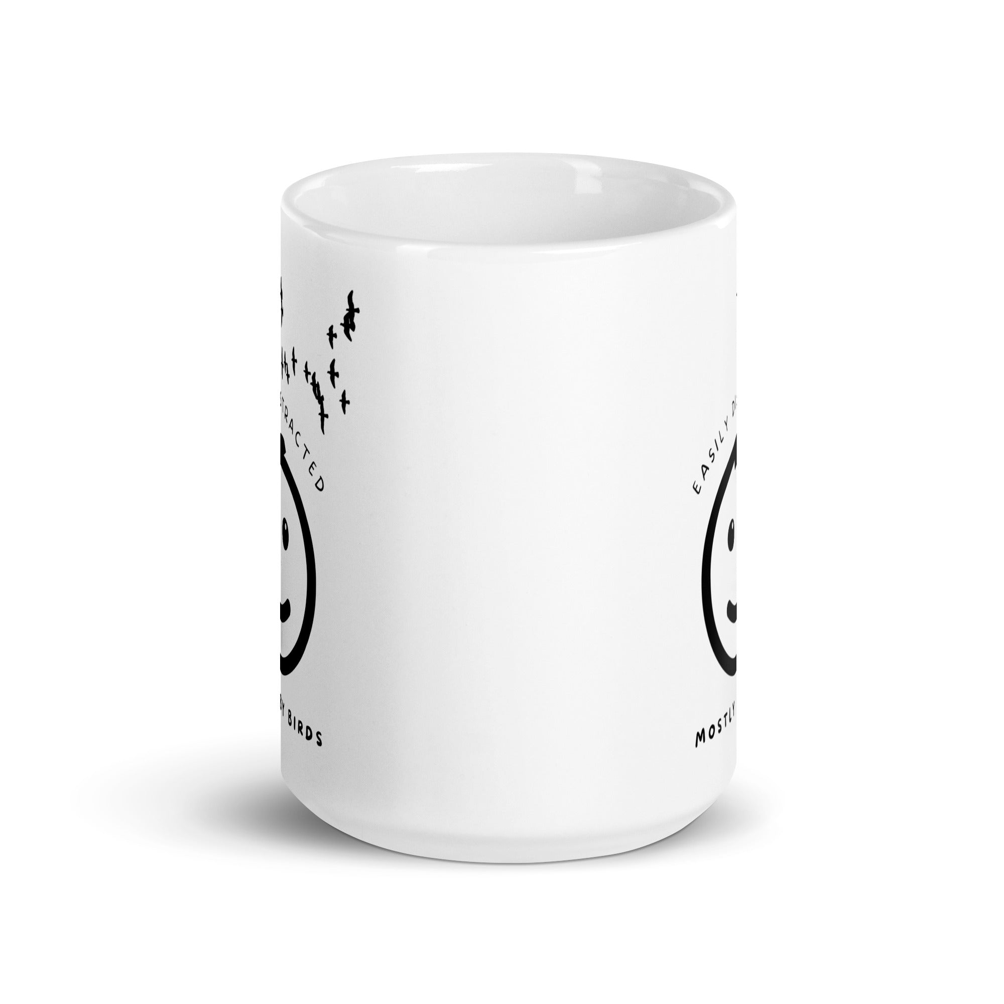 White 15oz mug with the words "Easily distracted, mostly by Birds" surrounding a smiley face with eyes looking up toward a flock of birds.