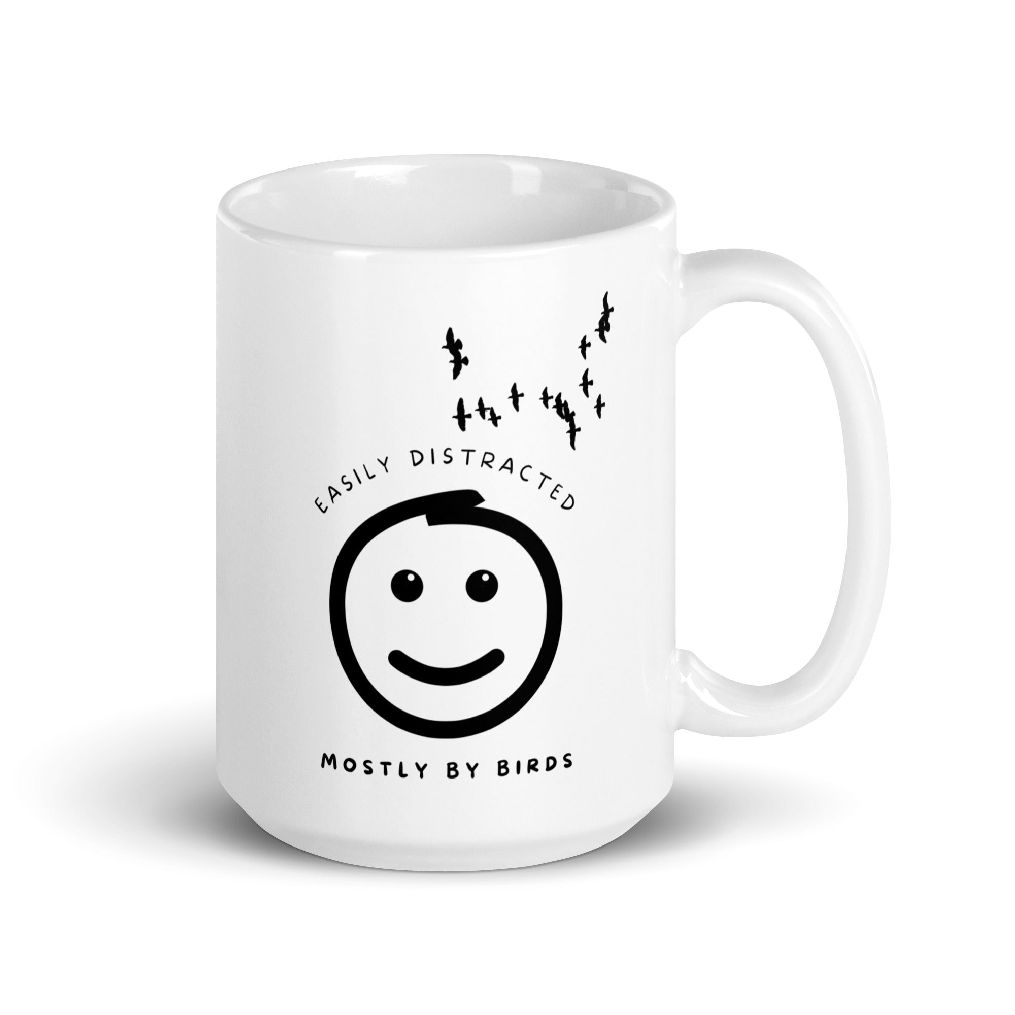 White 15oz mug with the words "Easily distracted, mostly by Birds" surrounding a smiley face with eyes looking up toward a flock of birds.