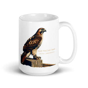 White 15oz mug with an illustration of a Red-Tailed Hawk on a fence and the common and scientific names next to the illustration.