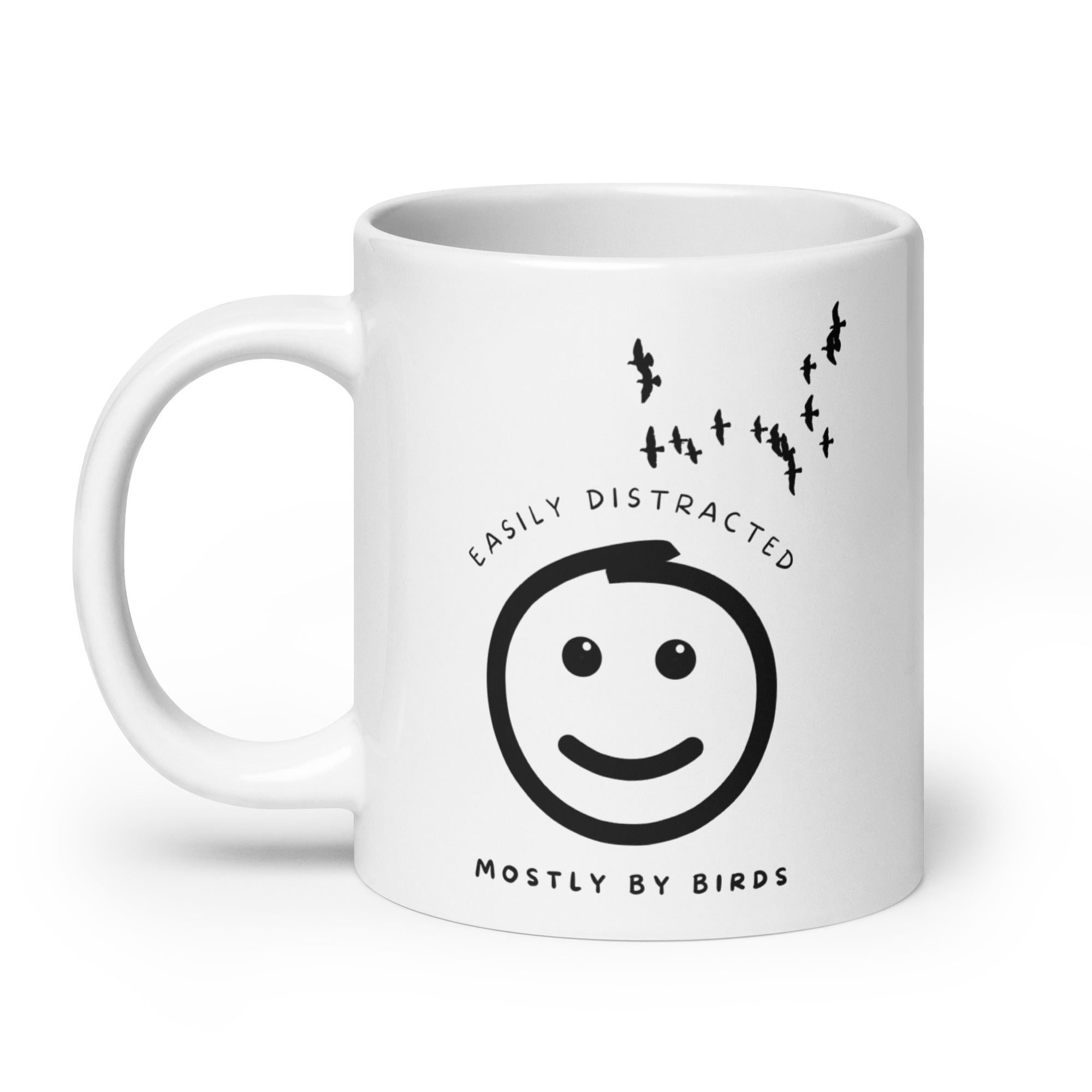 White 20oz mug with the words "Easily distracted, mostly by Birds" surrounding a smiley face with eyes looking up toward a flock of birds.