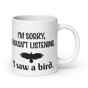 White 20oz mug with the words "I'm Sorry I Wasn't Listening. I Saw a Bird." around the silhouette of a bird flying.