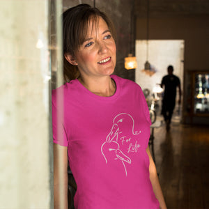 Bright pink unisex bird shirt featuring a line drawing of two Albatross heads and the words "For Life" on the front. Worn by a woman leaning against a wall in a restaurant.