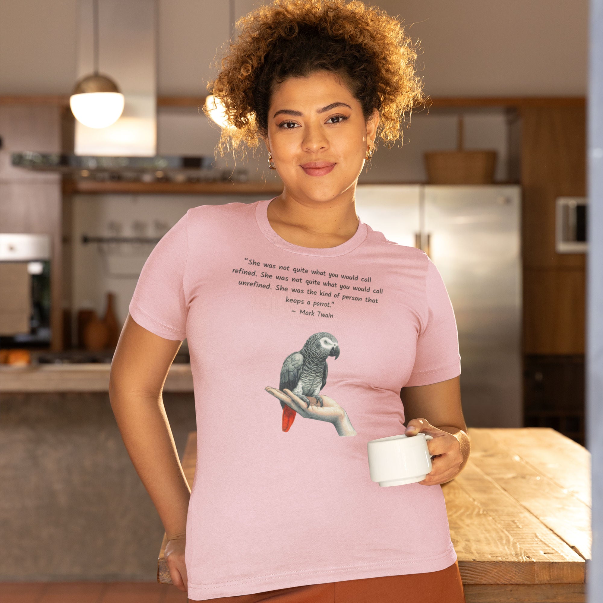 Pink bird shirt with a Mark Twain woman who keeps parrot quote and a illustration of an african grey parrot perched on a hand beneath. Worn by a woman.