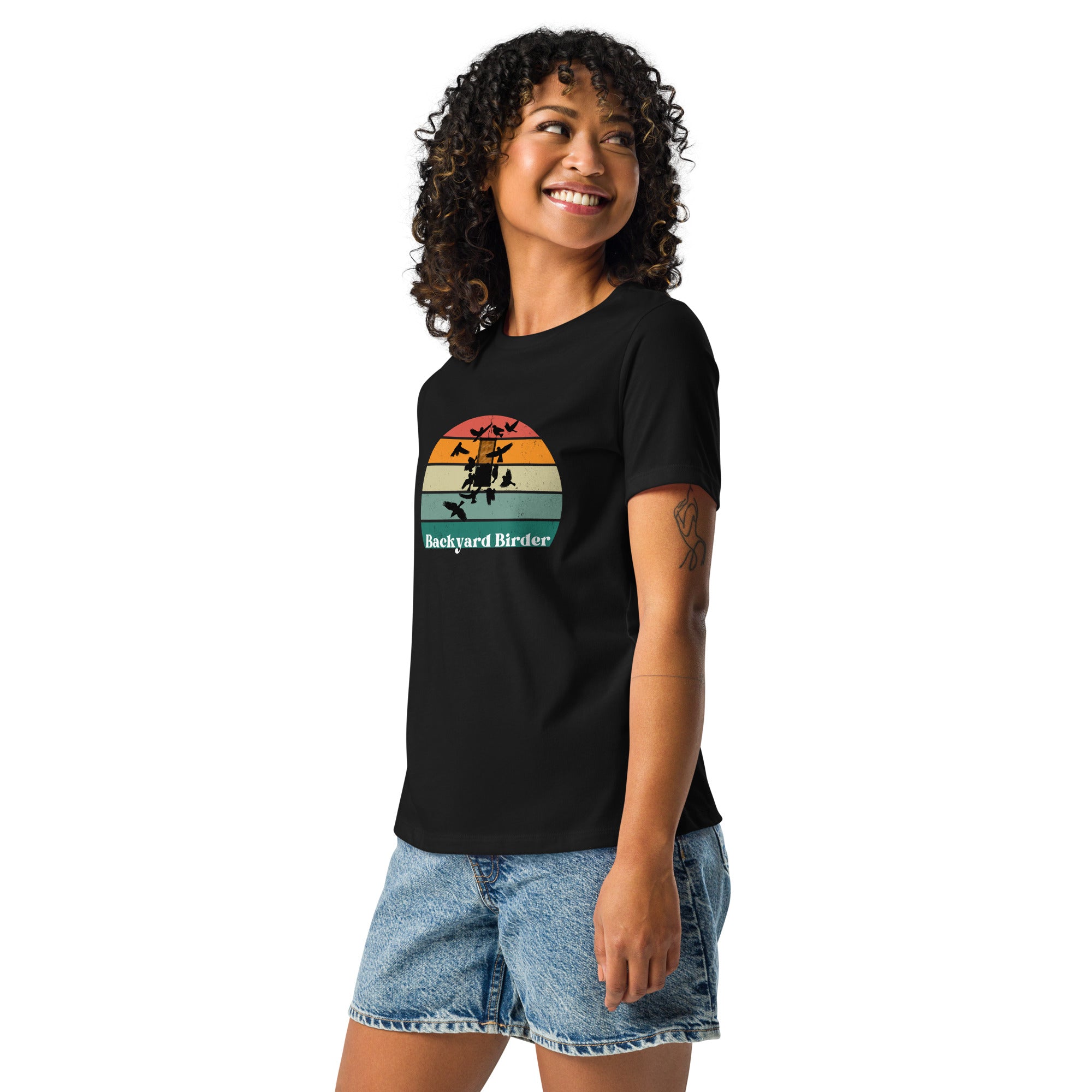 A black women's bird shirt with a retro sun design outlining a bird feeder with the words Backyard Birder. Worn by a woman.